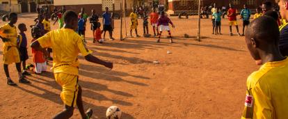 Volunteers watch their students play a game of football in Ghana. Students practice their football skills in Ghana.